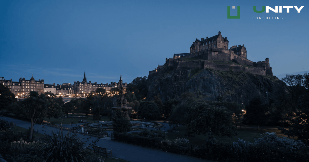 A wide shot of Edinburgh Castle and the Old Town at blue hour, with city lights twinkling below.