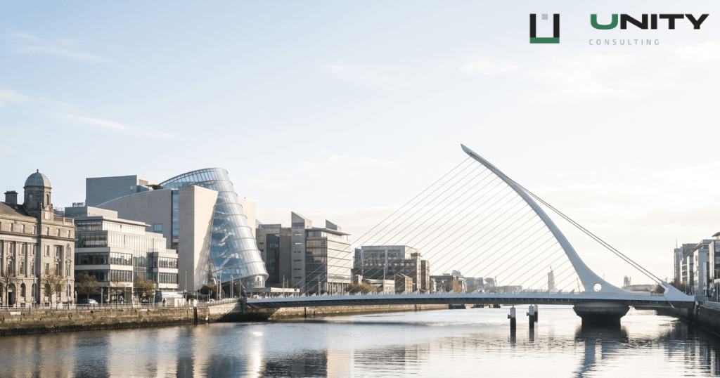A wide-angle view of modern Dublin along the River Liffey, featuring the Samuel Beckett Bridge under a bright sky.