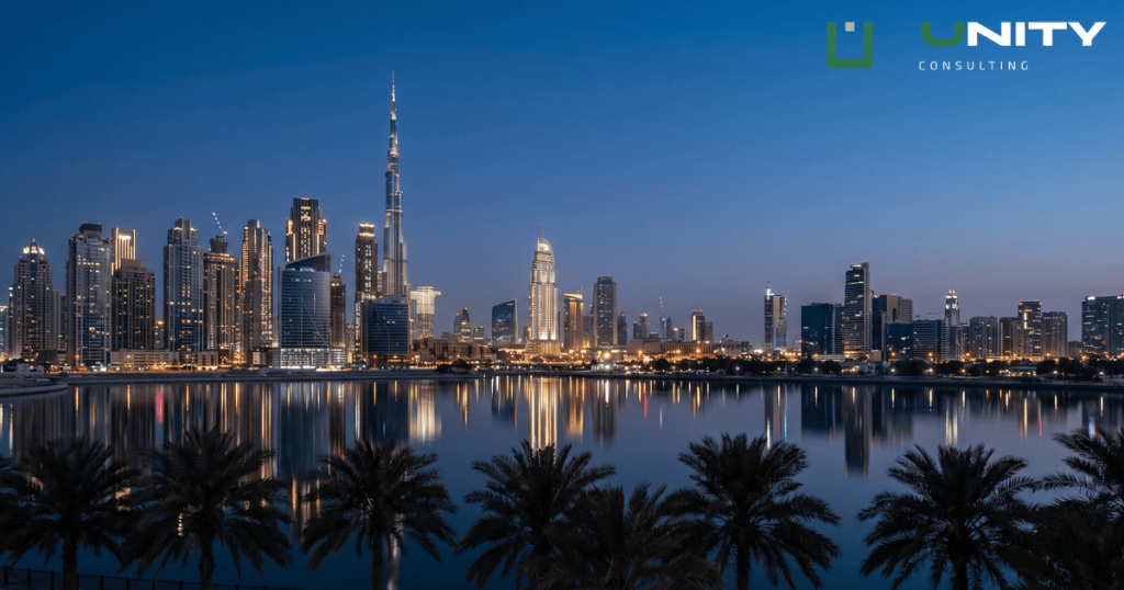 A wide-angle view of Dubai's illuminated skyscrapers at blue hour, reflected in still water with dark palm tree silhouettes.