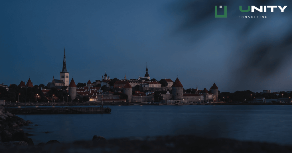 A wide shot of Tallinn Old Town at blue hour, with historic spires silhouetted against a dark blue sky.