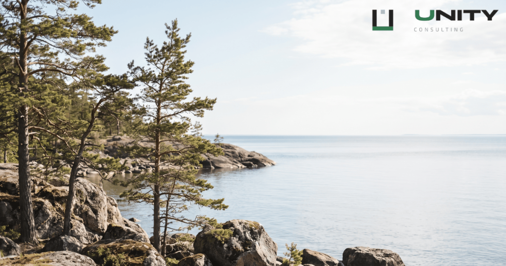 A wide, sunlit view of the rocky Baltic Sea coastline and pine trees in Lahemaa National Park, Estonia.