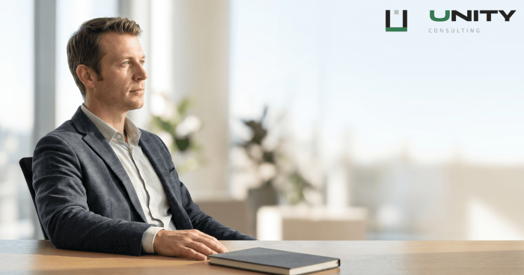 A pensive entrepreneur sits at a modern desk, looking into the distance with a thoughtful expression.