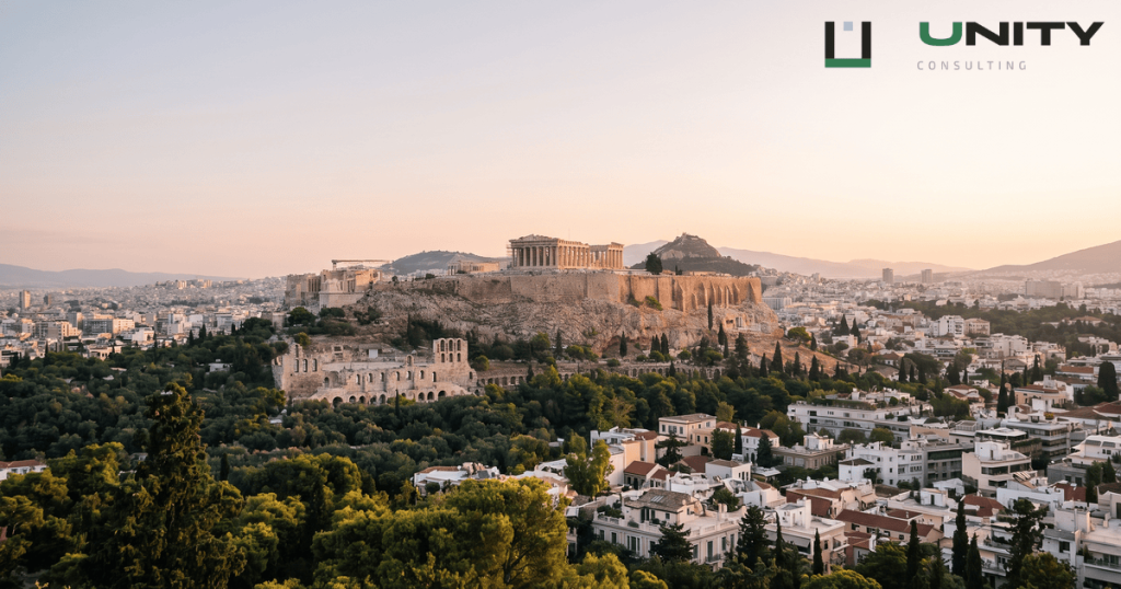 An elevated, wide-angle view of Athens at golden hour, with the Acropolis visible in the distance.