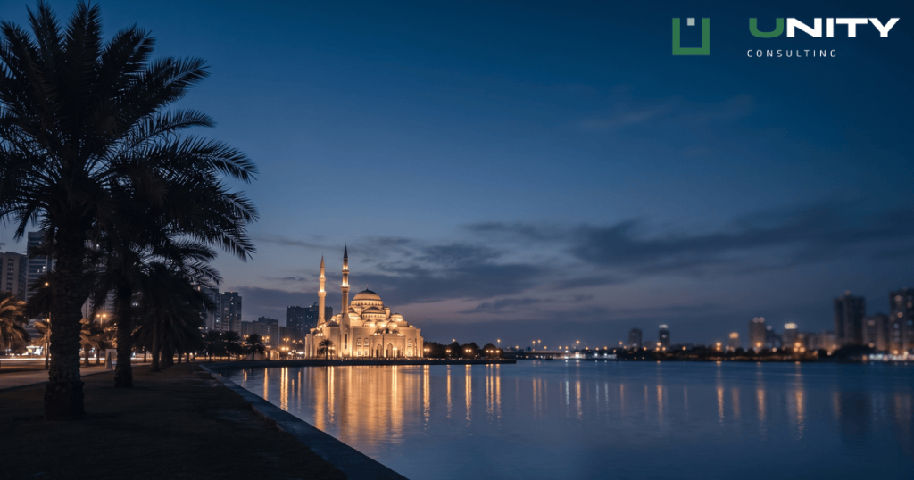 A blue hour wide shot of Sharjah's Khalid Lagoon with the illuminated Al Noor Mosque across the water.